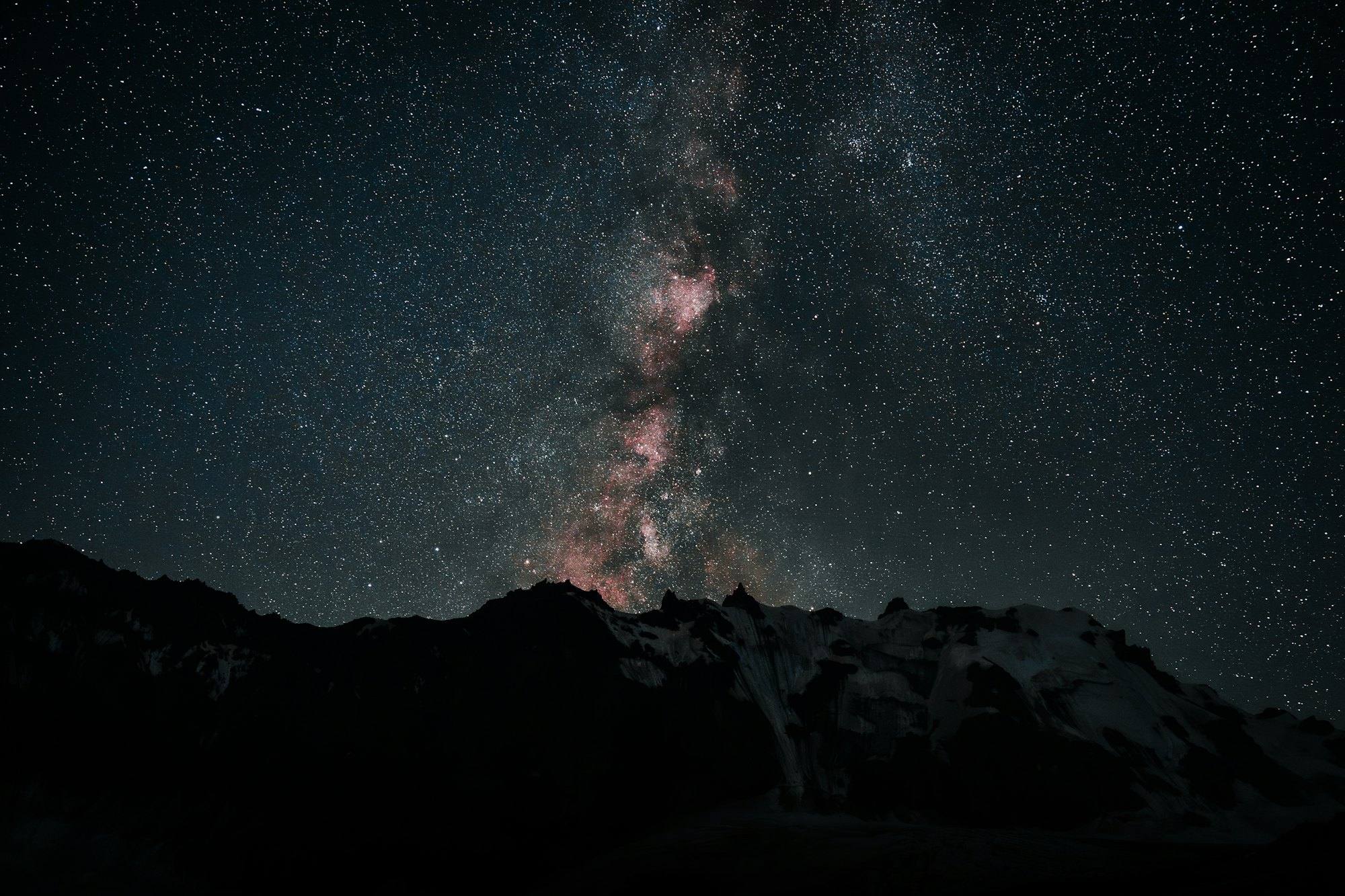 The Milky Way rising over a dark, jagged mountain ridge
