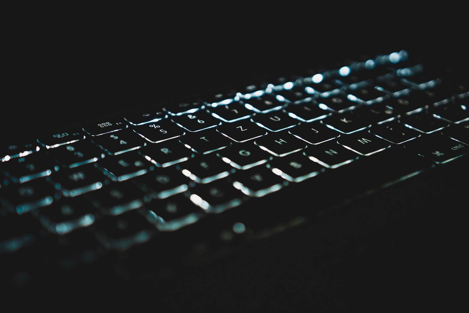 Backlit keys of a dark keyboard glowing in a dim room
