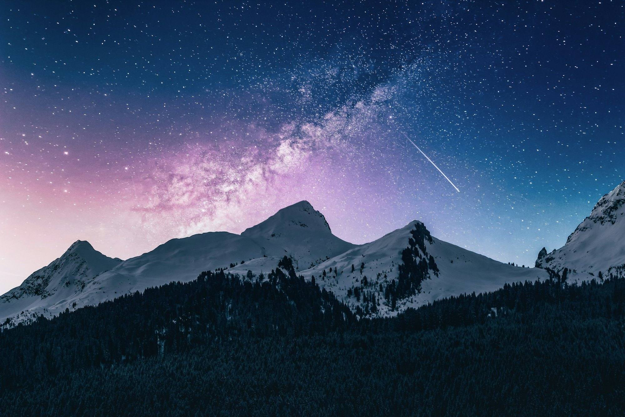 Snow-covered peaks under a violet Milky Way